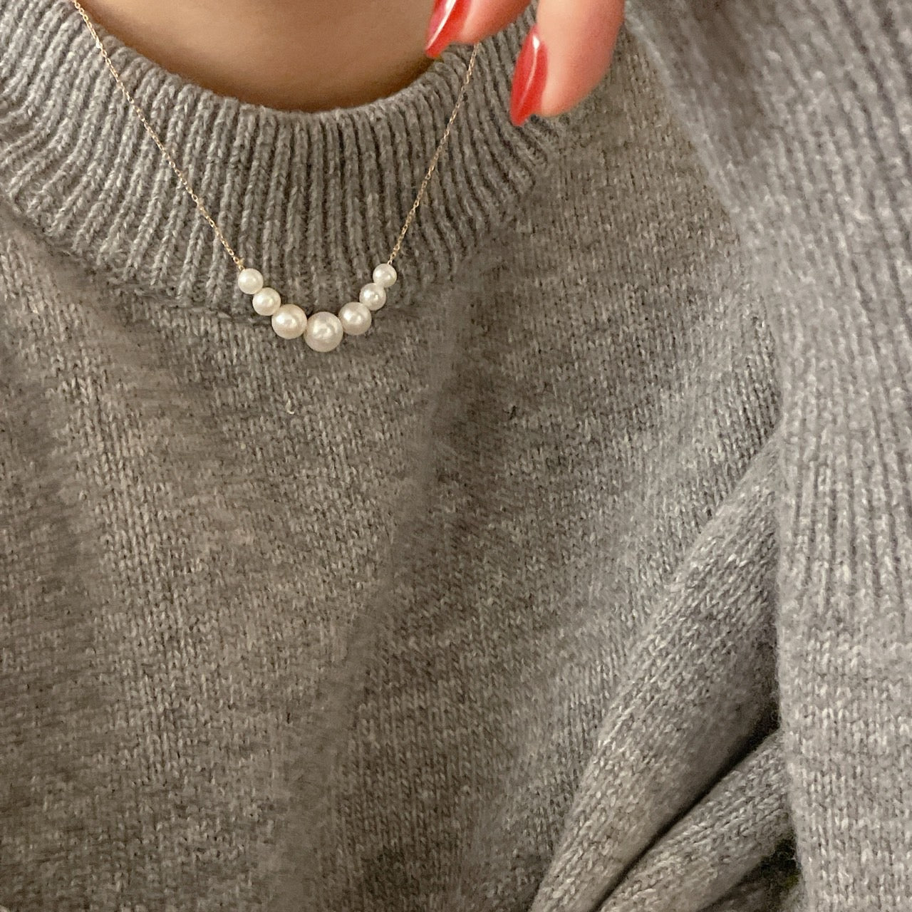 Close-up of woman wearing 14k solid gold necklace with floating freshwater pearls, styled for a sophisticated look.